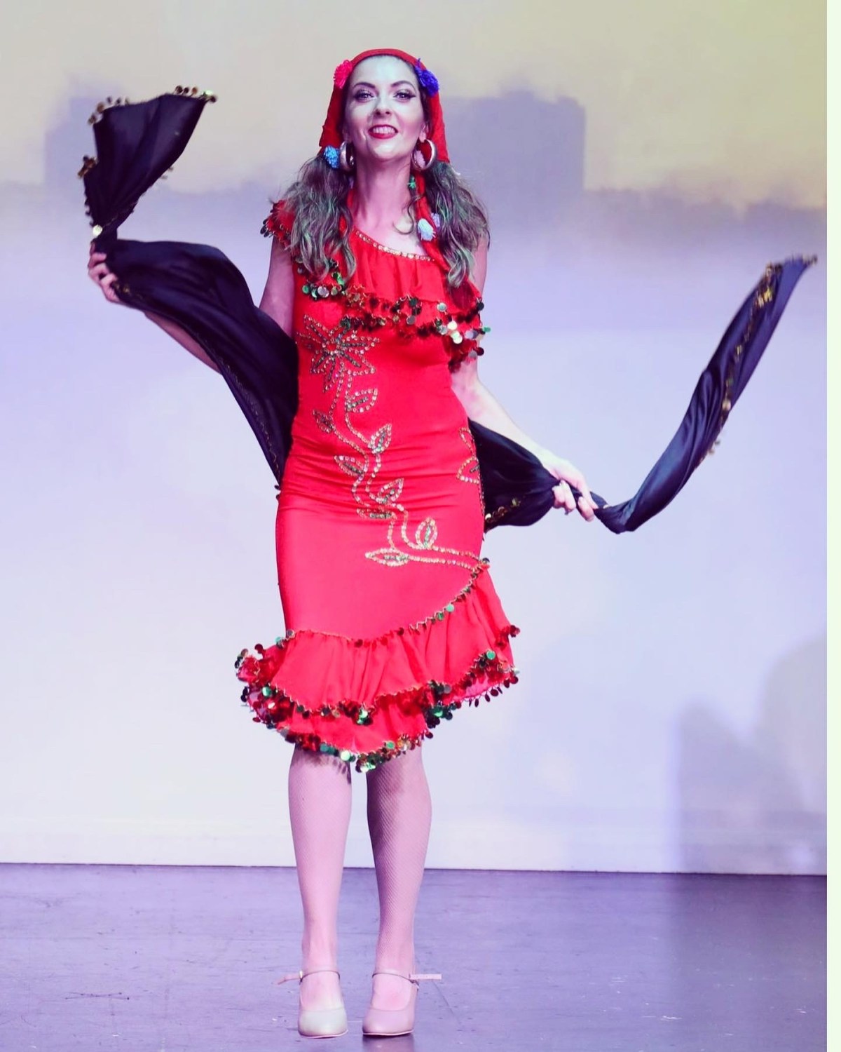Folkloric performance in a red coin-trimmed dress with black veils